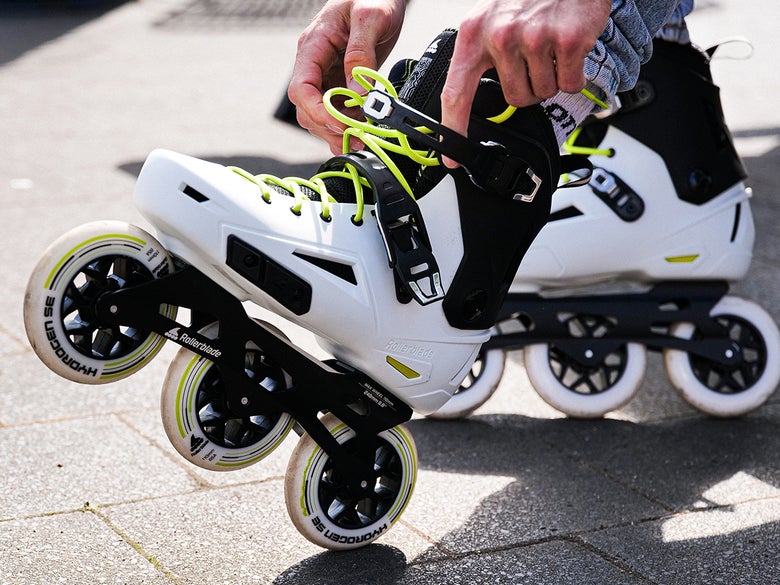 Close up shot of a person fastening a pair white Rollerblade Lightning 110 skates to their feet