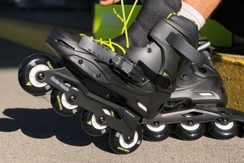 A person laces up sleek black inline skates with bright green laces. The skates feature four wheels. The scene conveys a sense of readiness and excitement for outdoor skating.